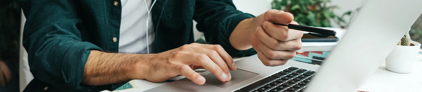 Gentleman's hand pointing to a laptop screen while holding a pen