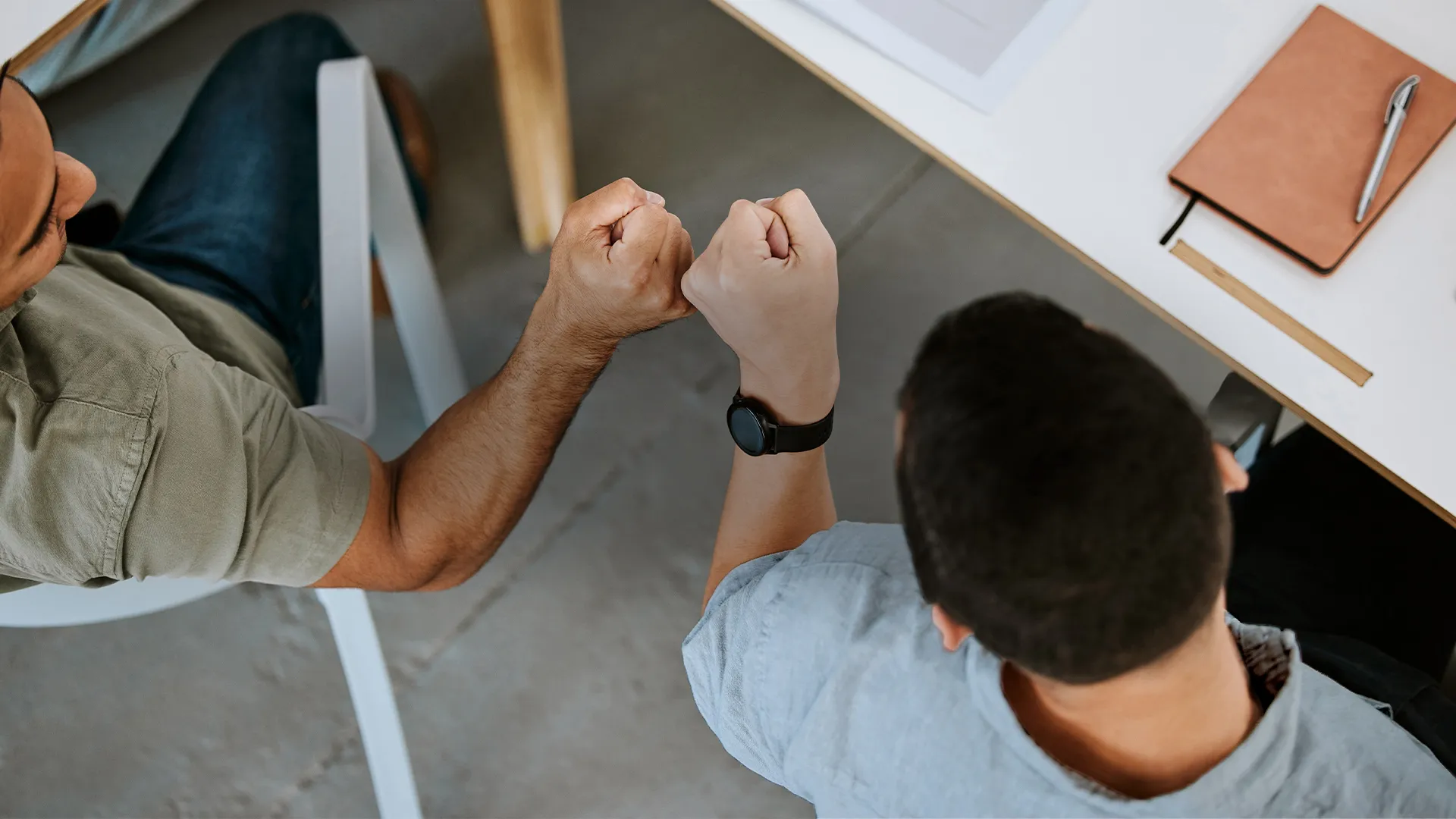 Two male employees fist bumping at meeting